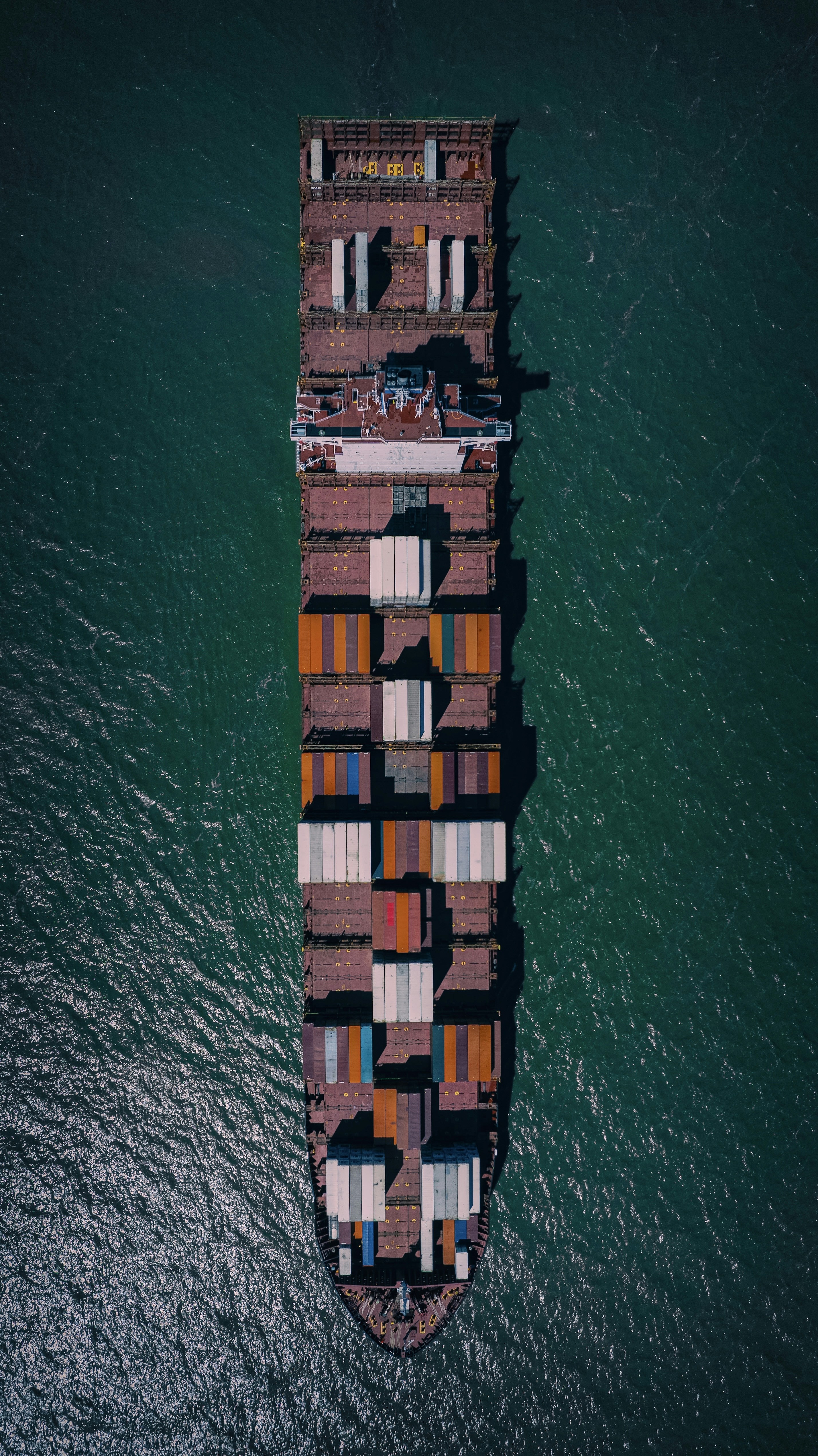 Large container ship loaded with colorful cargo containers at port, aerial view, blue ocean